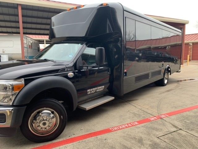 A black bus is parked in a parking lot in front of a building.