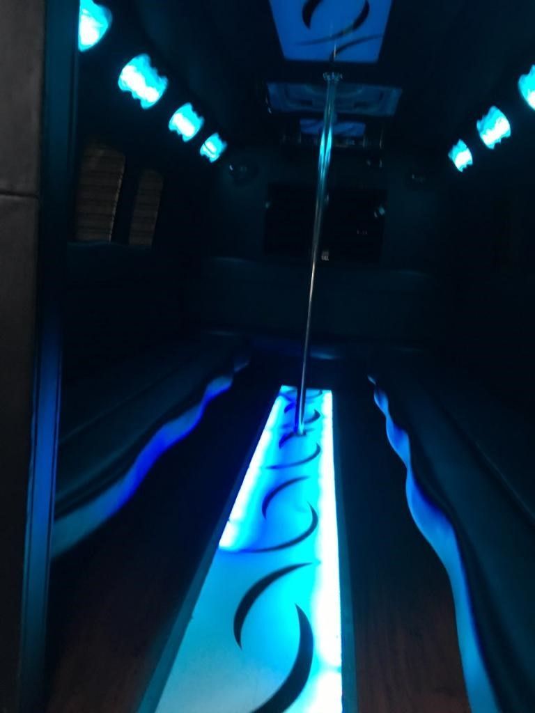 The inside of a limousine with blue lights and a pole