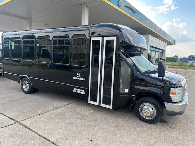 A black bus is parked in front of a gas station