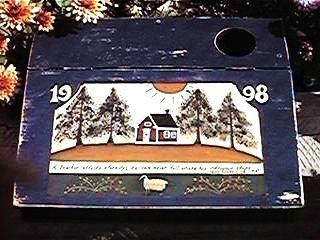 Blue wooden box with a painted folk art scene of a house, trees, sun, and sheep, dated 1998.