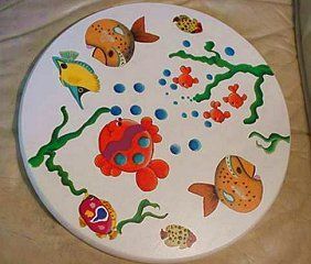Round white tabletop with colorful painted fish, bubbles, and seaweed.