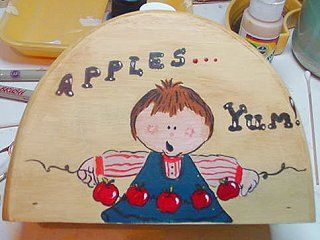 Wooden food cover with child holding apples. Brown hair, blue dress. 