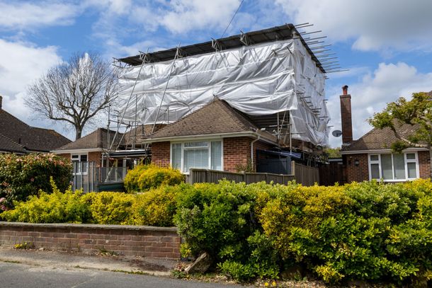 Une maison avec une bâche dessus est en cours de rénovation.