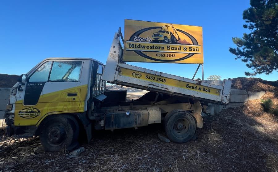 A dump truck with a sign on the back that says midwestern sand & soil — Pigot's Mid Western Sand and Soil In Orange, NSW