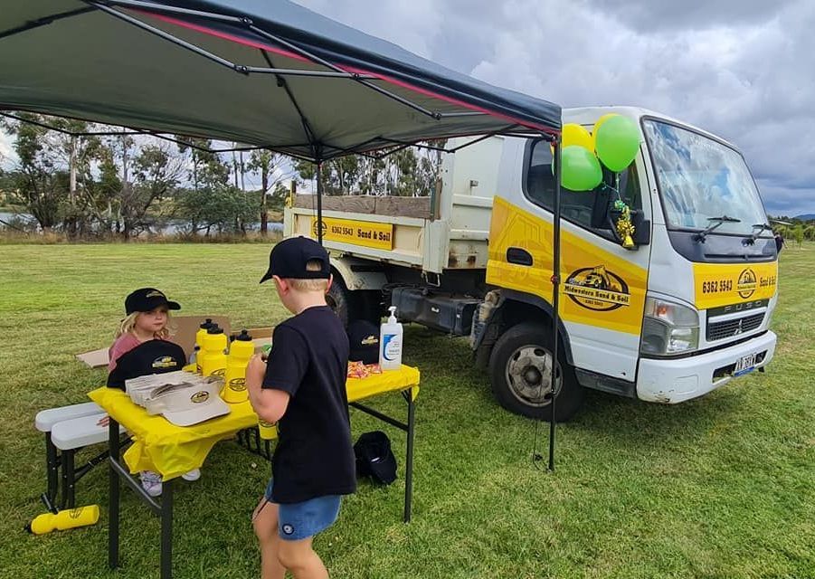 A boy is standing in front of a dump truck in a field — Pigot's Mid Western Sand and Soil In Orange, NSW