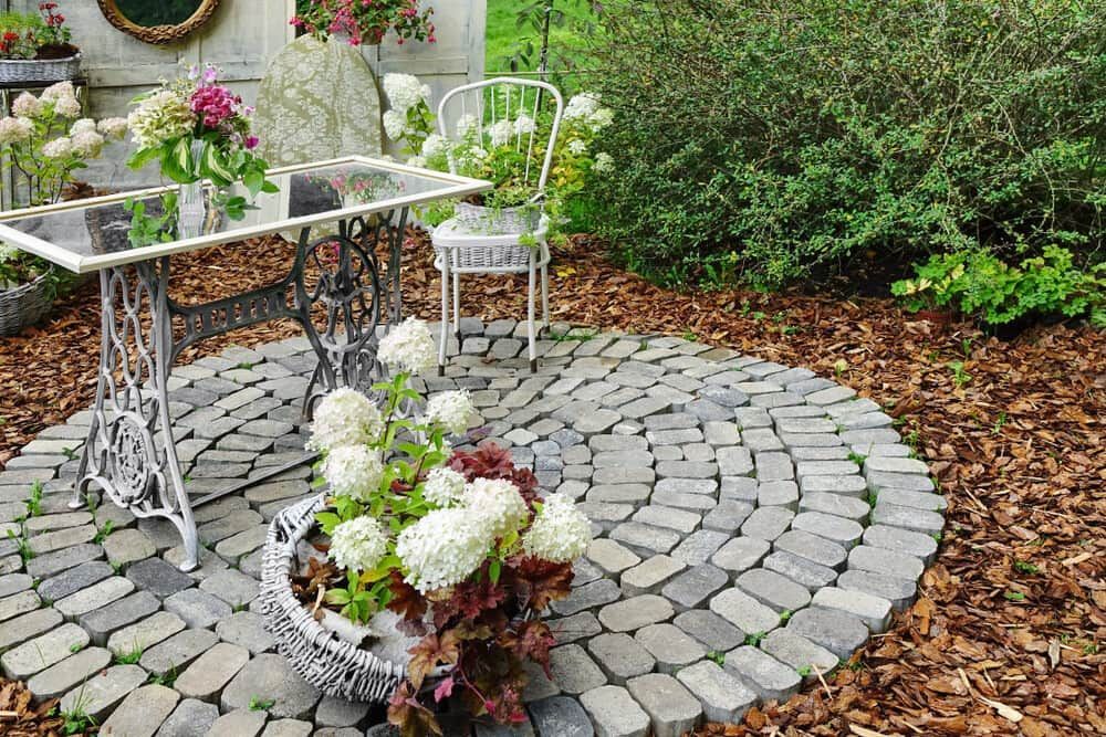 A Table And Chairs Are Sitting On A Brick Patio Surrounded By Flowers — Pigot's Mid Western Sand and Soil In Orange, NSW