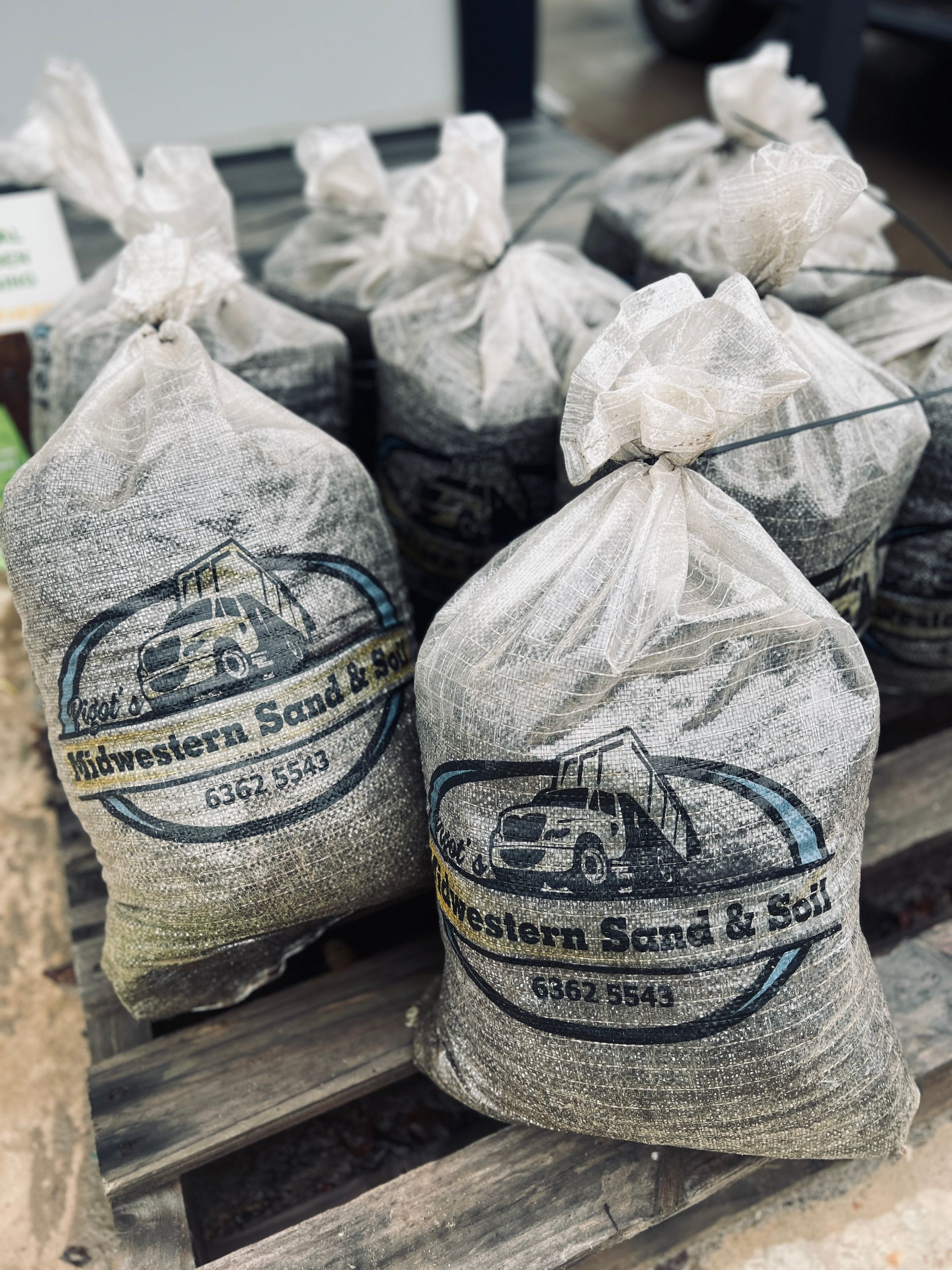 A bunch of bags of sand are sitting on a wooden pallet — Pigot's Mid Western Sand and Soil In Orange, NSW