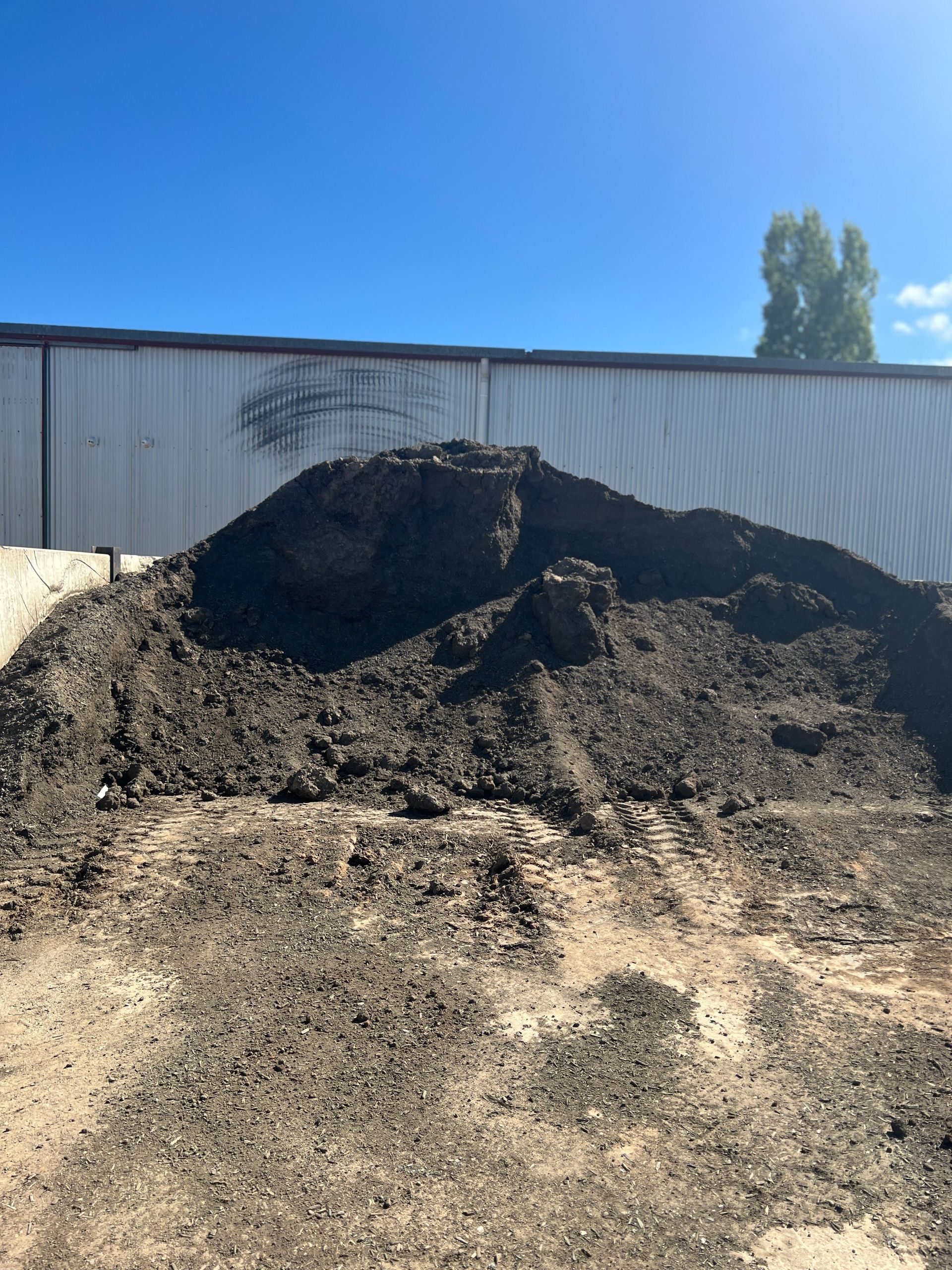 A large pile of dirt is sitting in front of a building — Pigot's Mid Western Sand and Soil In Orange, NSW