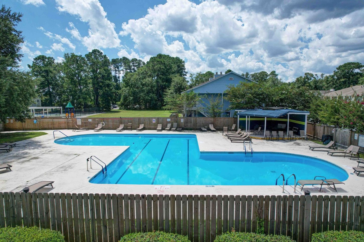 A large swimming pool surrounded by chairs and a wooden fence.