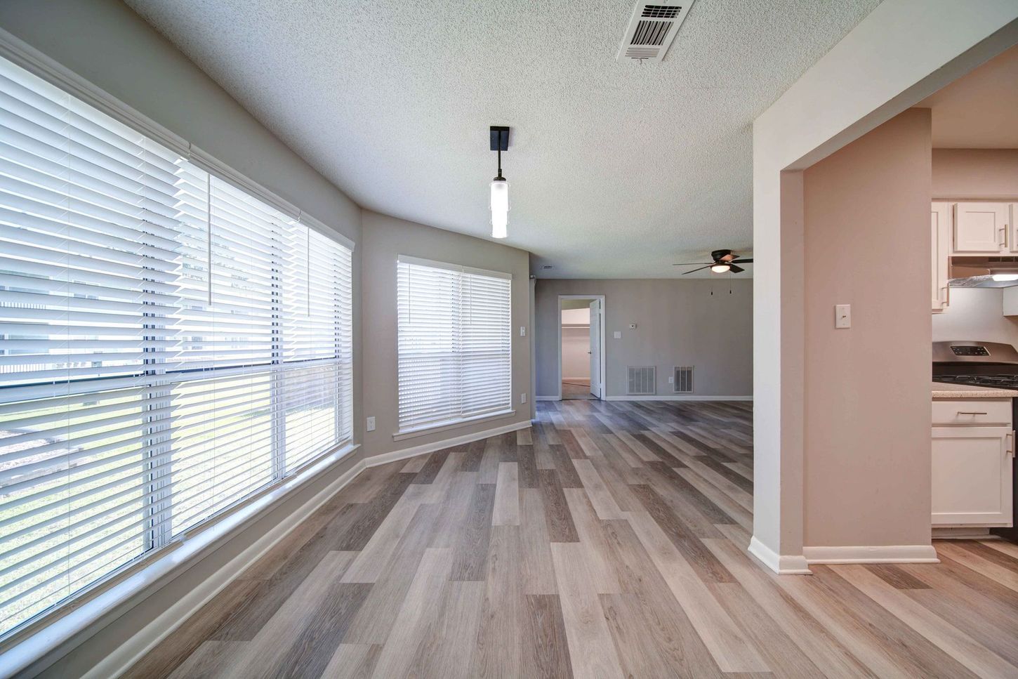 An empty living room with hardwood floors and lots of windows.