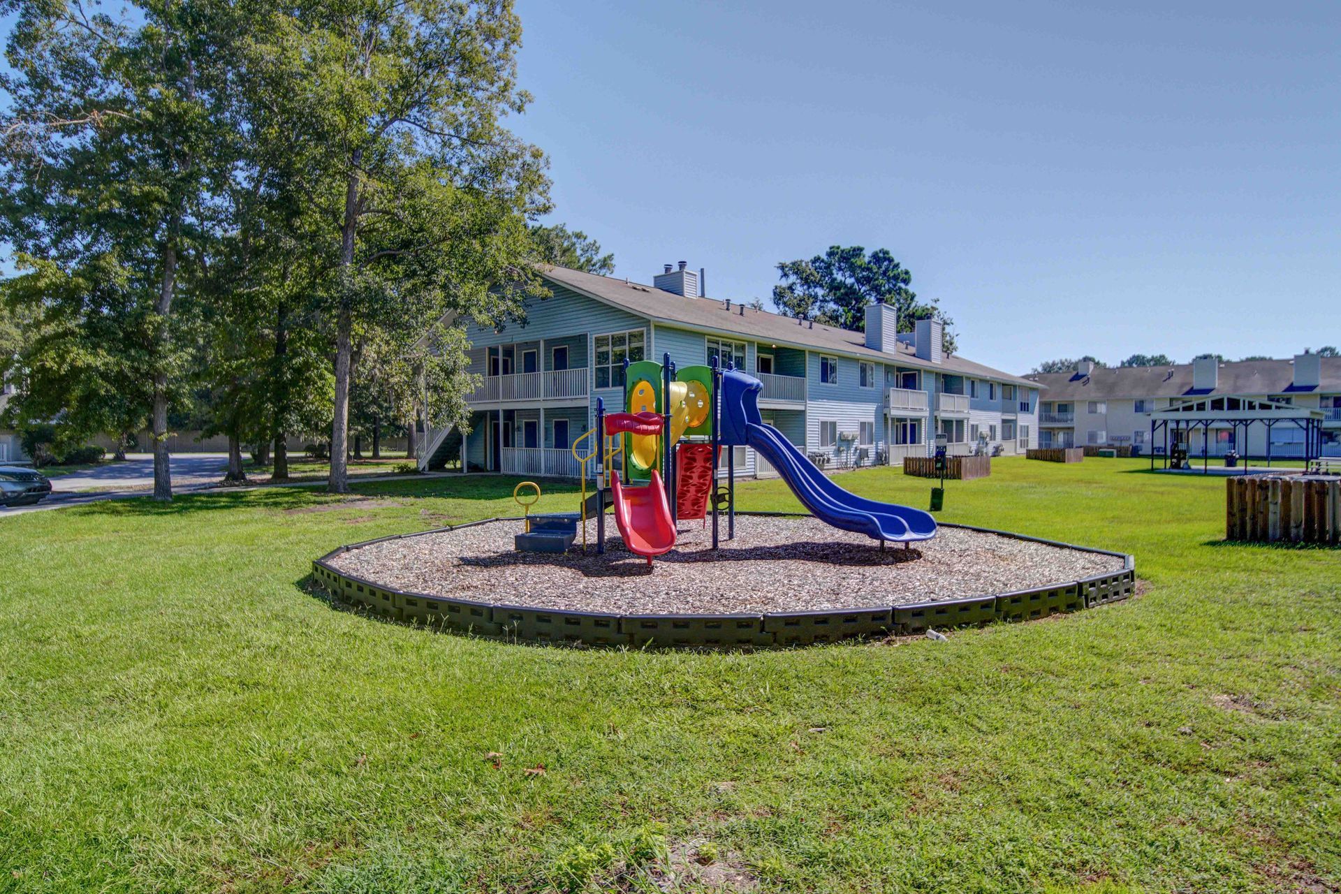 There is a playground in the middle of a lush green field.