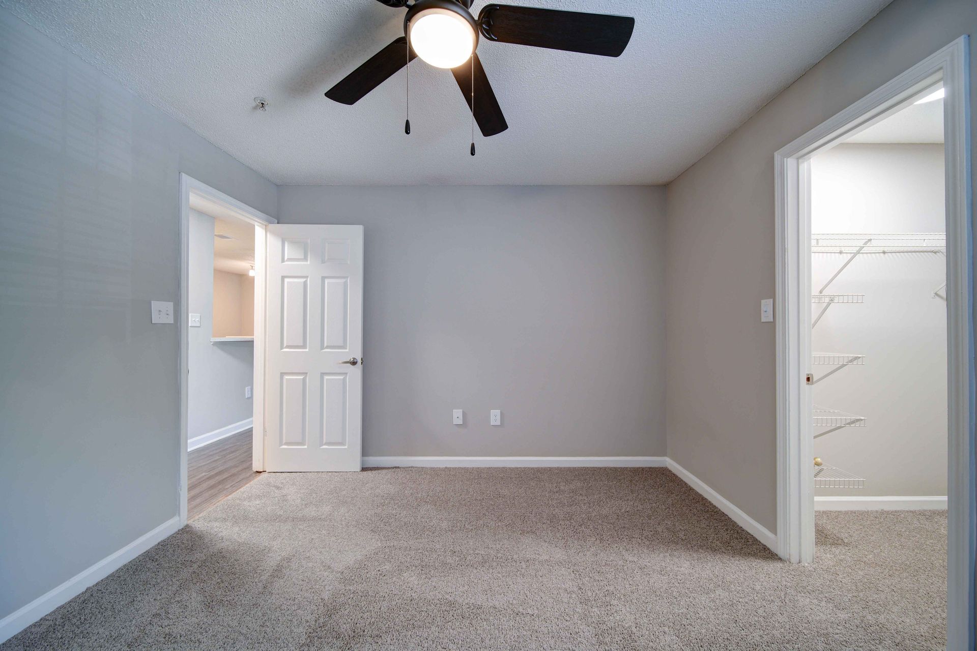 An empty bedroom with a ceiling fan and a closet.