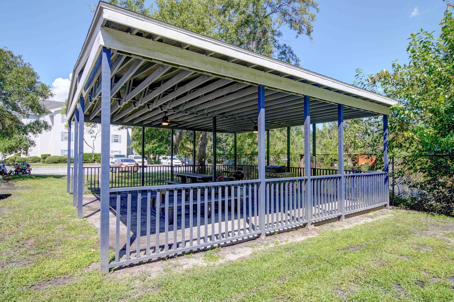 A blue and white covered picnic area with tables and chairs in a park.