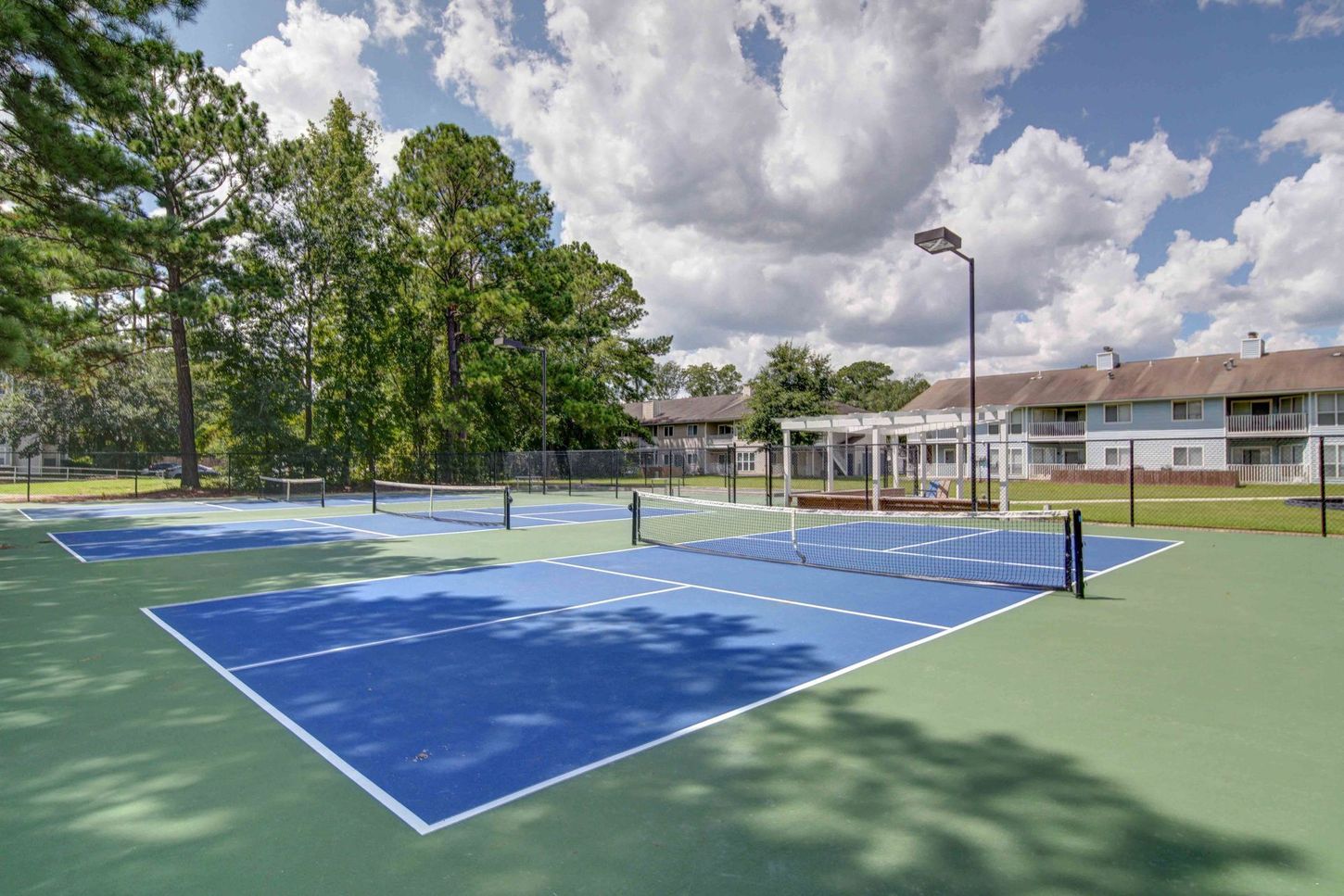 A tennis court with trees in the background and a building in the background.