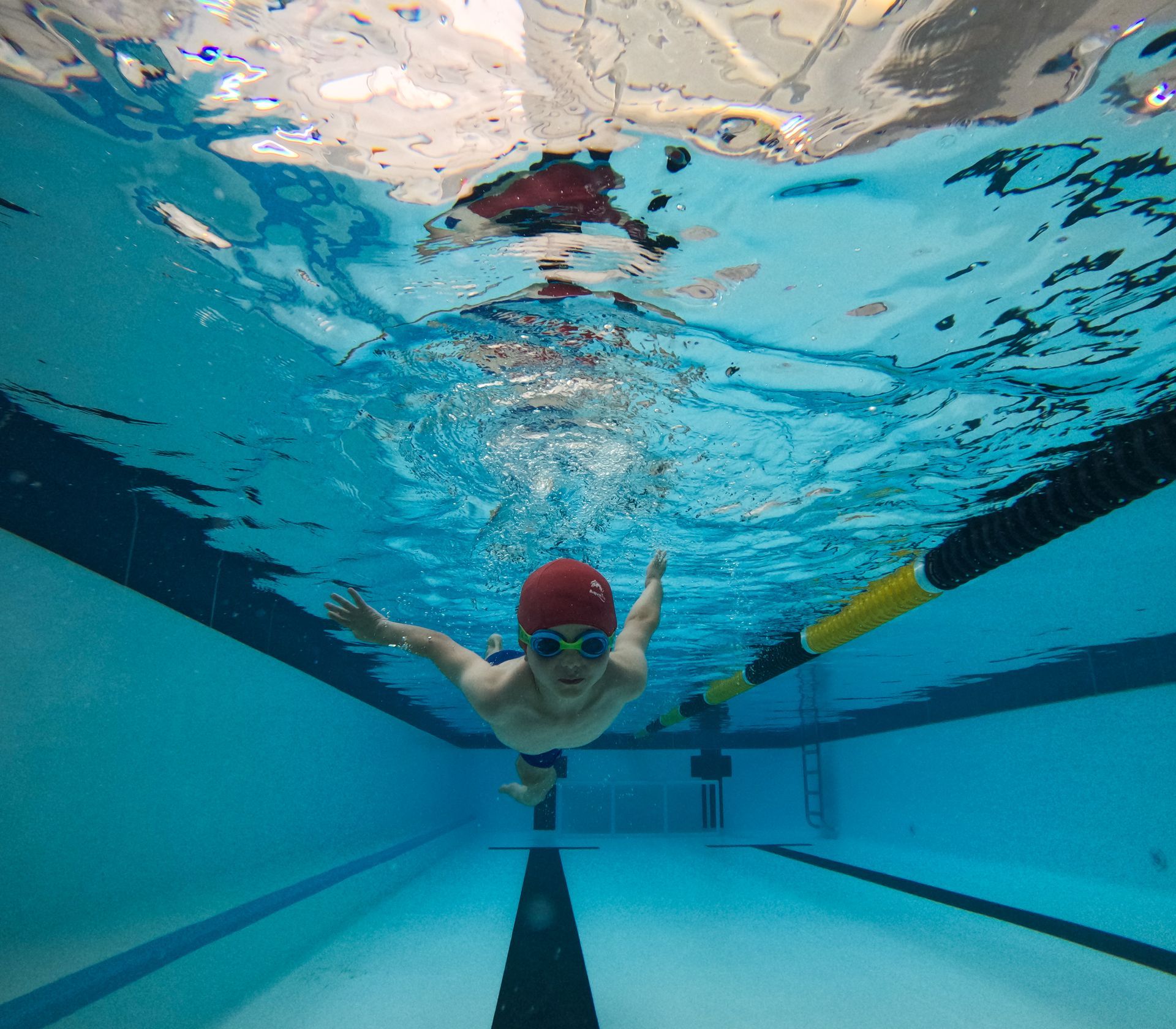 A person is swimming underwater in a swimming pool