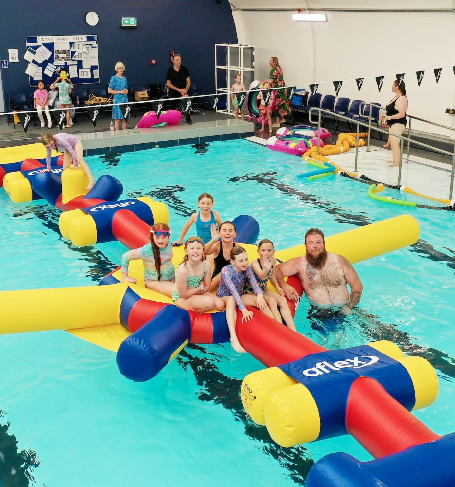 A group of people are sitting on inflatable rafts in a swimming pool