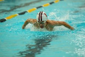 A man is swimming in a swimming pool wearing a swim cap and goggles.