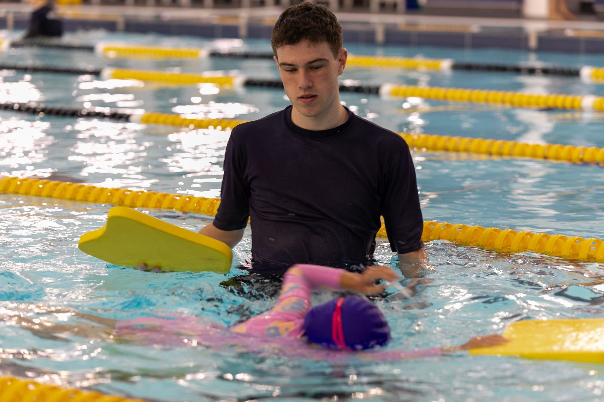 A man is teaching a child how to swim in a swimming pool.