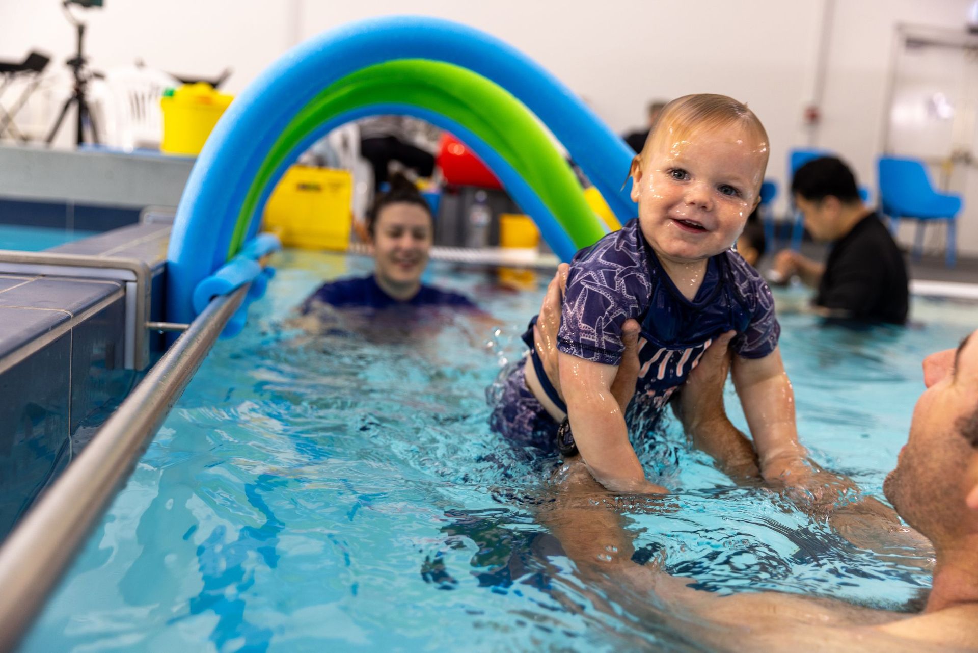 A man is holding a baby in a swimming pool.