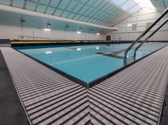 A large indoor swimming pool with stairs leading to it.