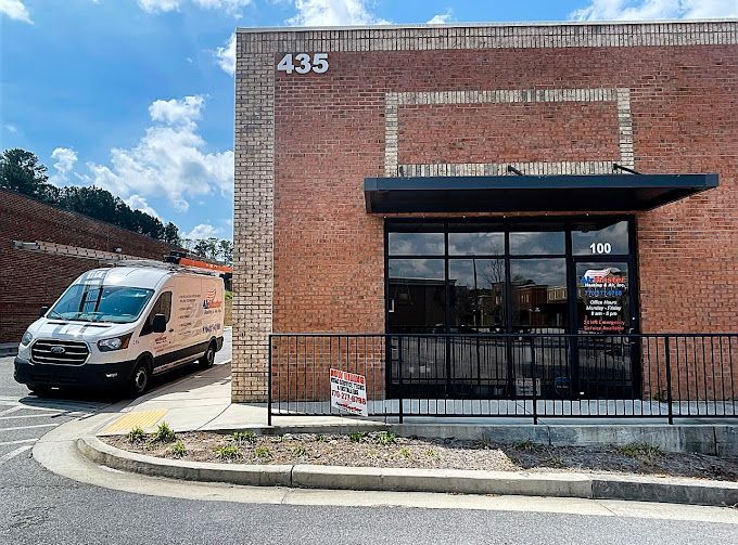 A white van is parked in front of a brick building.