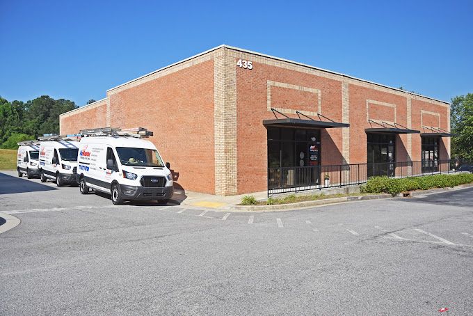 A row of vans are parked in front of a brick building.