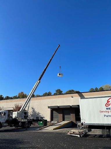 A truck with a crane attached to it is parked in front of a building.