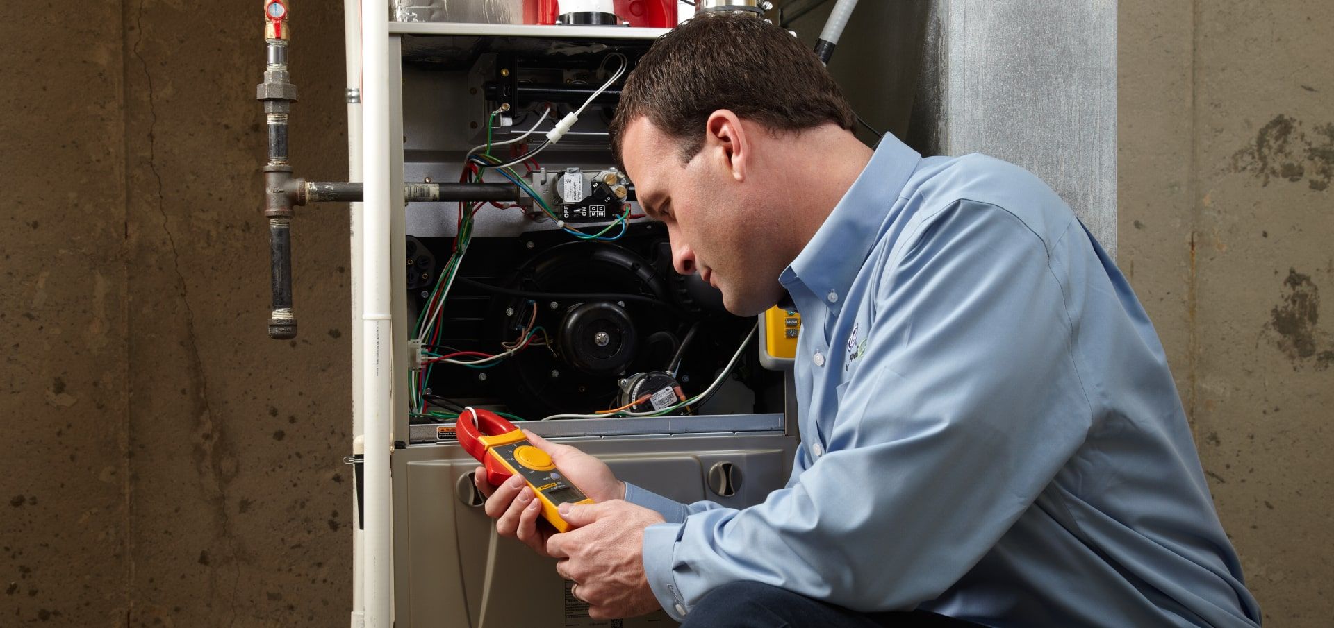 A man is working on a heater with a pair of pliers.