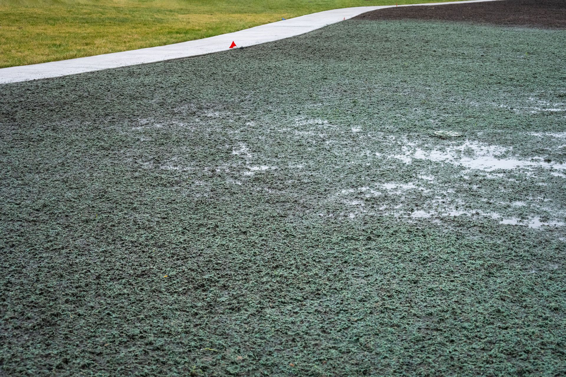 Snow-dusted artificial turf field with a white sideline and a small red marker near the top edge