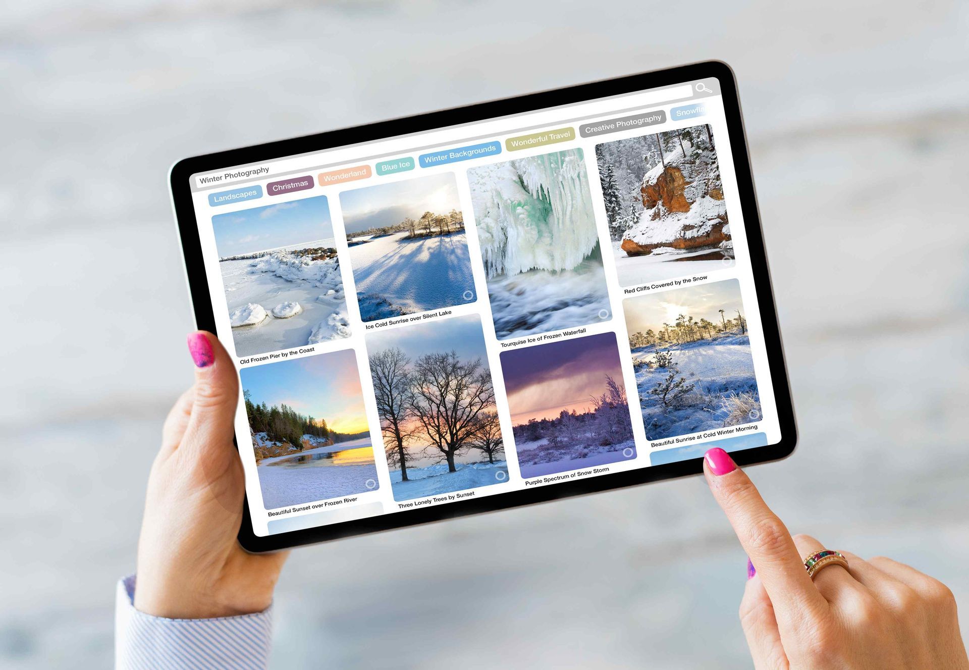 Image of 2 hands holding a tablet that has a photo gallery on the screen