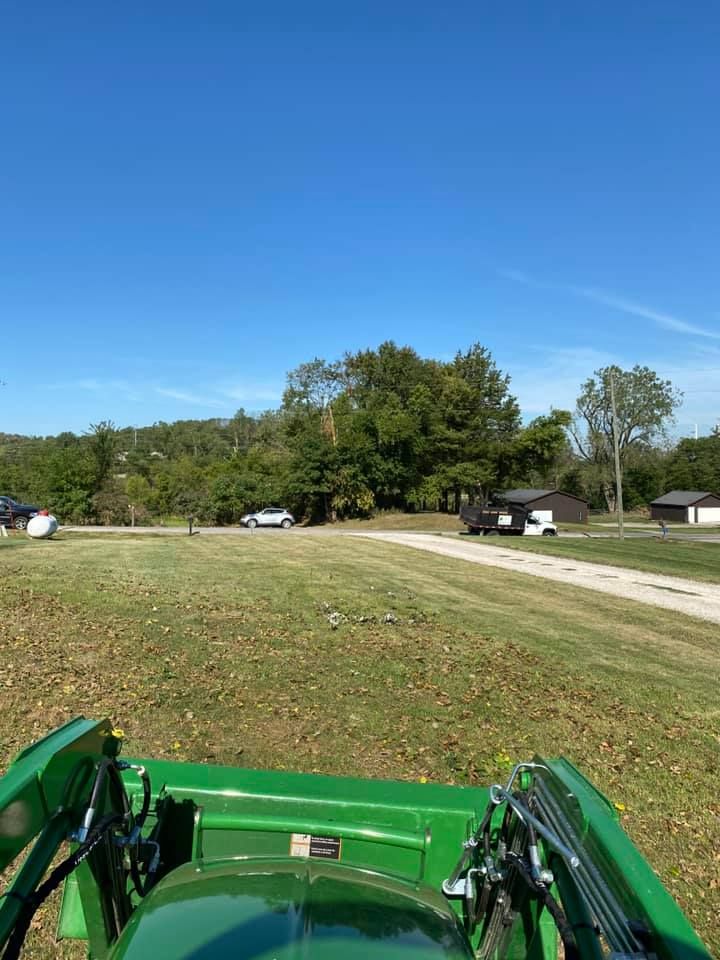 A green tractor is driving down a dirt road in a field.