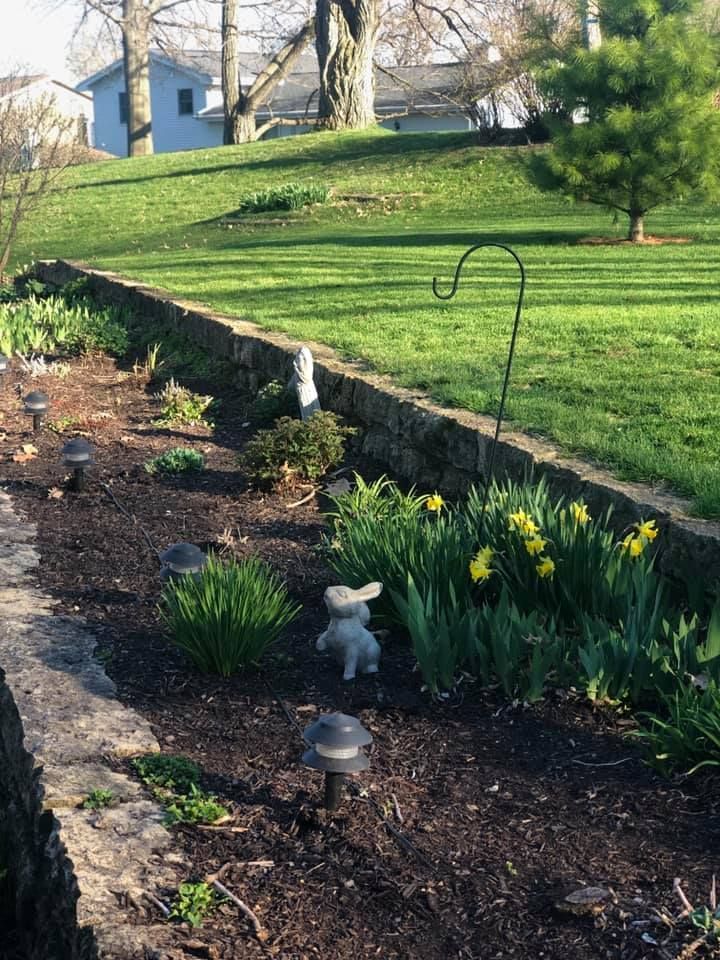 A garden with a stone wall and a statue of a rabbit