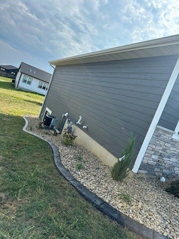 A house with a gray siding and a concrete curb in front of it.