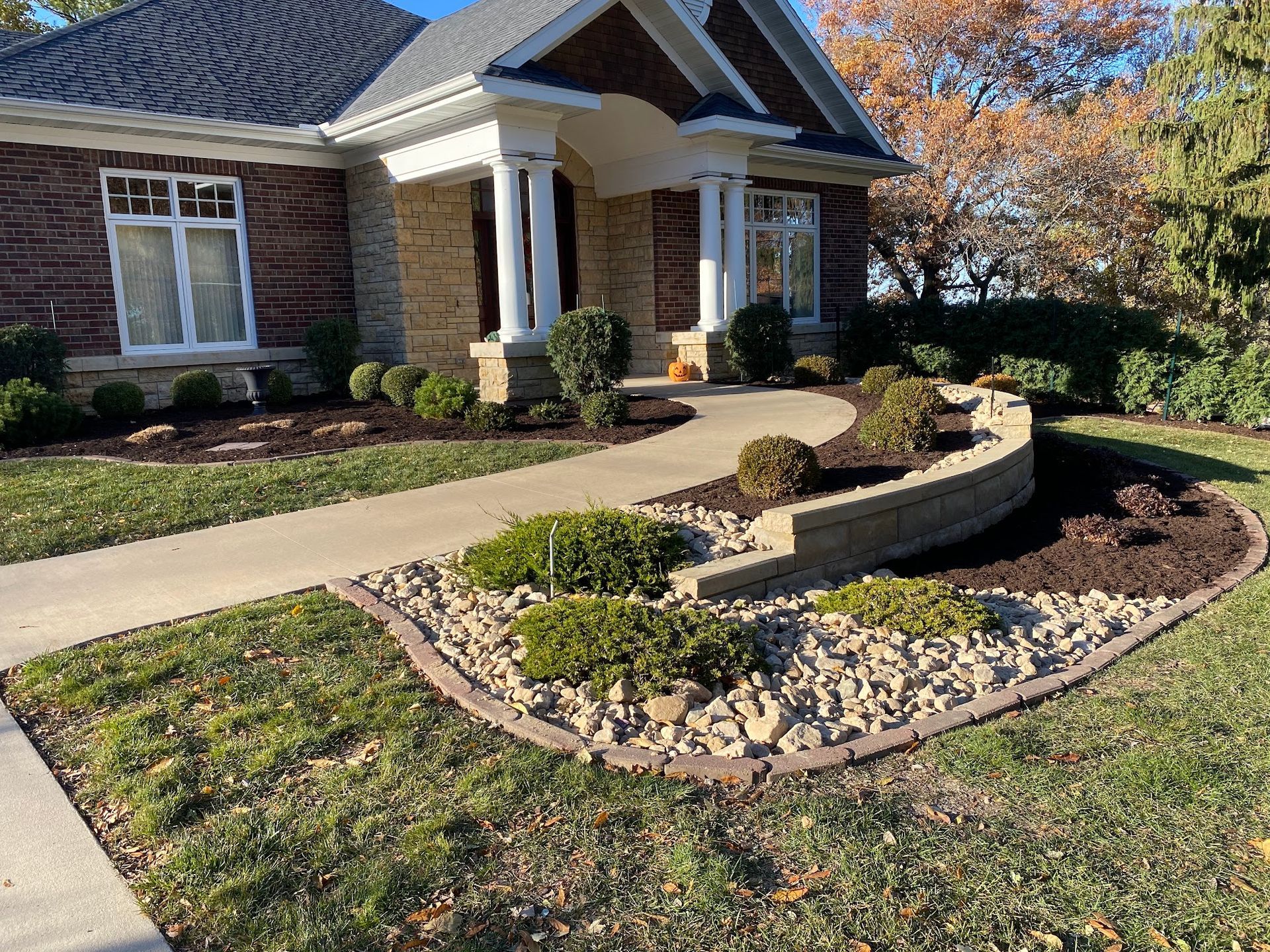 A large brick house with a lush green lawn and a walkway leading to it.