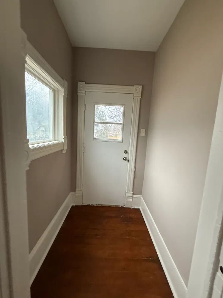 A hallway with a white door and a window.