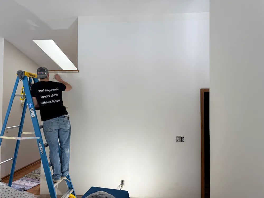 A man is standing on a ladder working on a wall