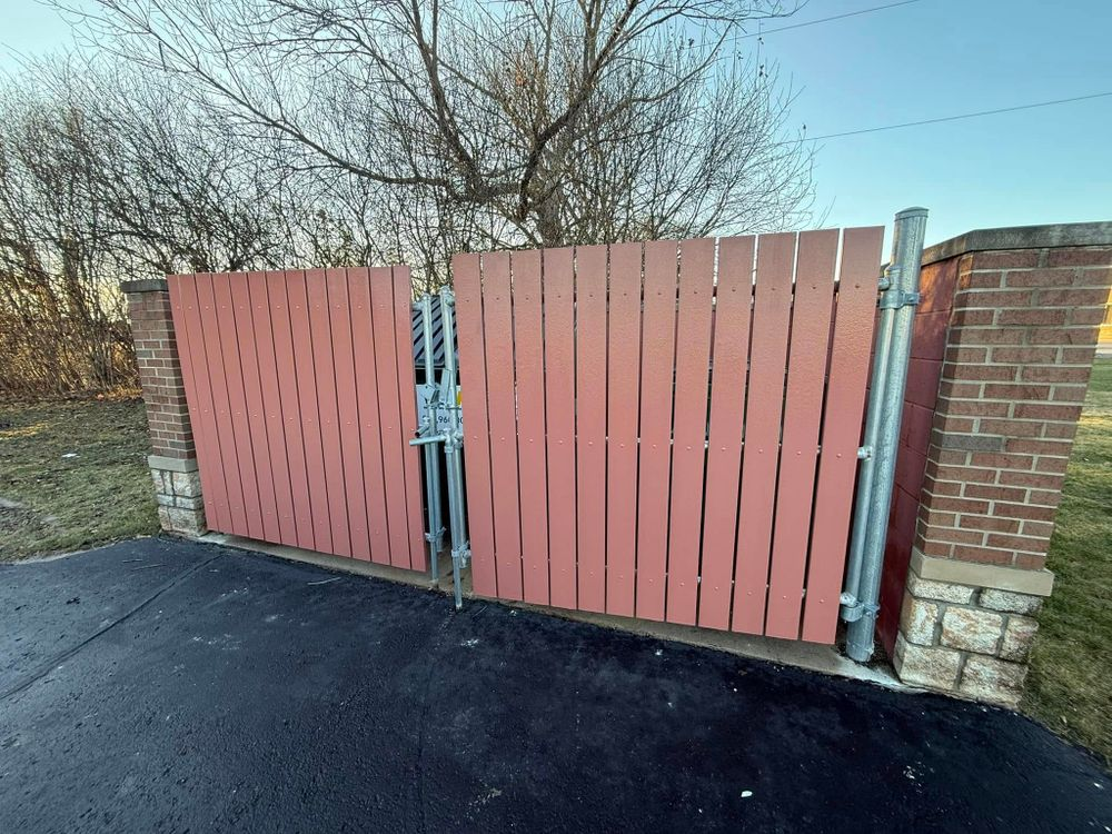 A red wooden fence is sitting next to a brick wall.