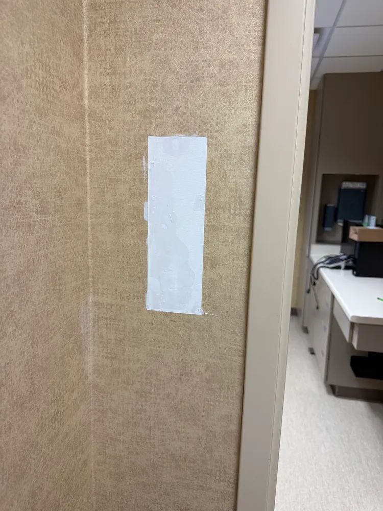 A white piece of paper is taped to a wall next to a door.