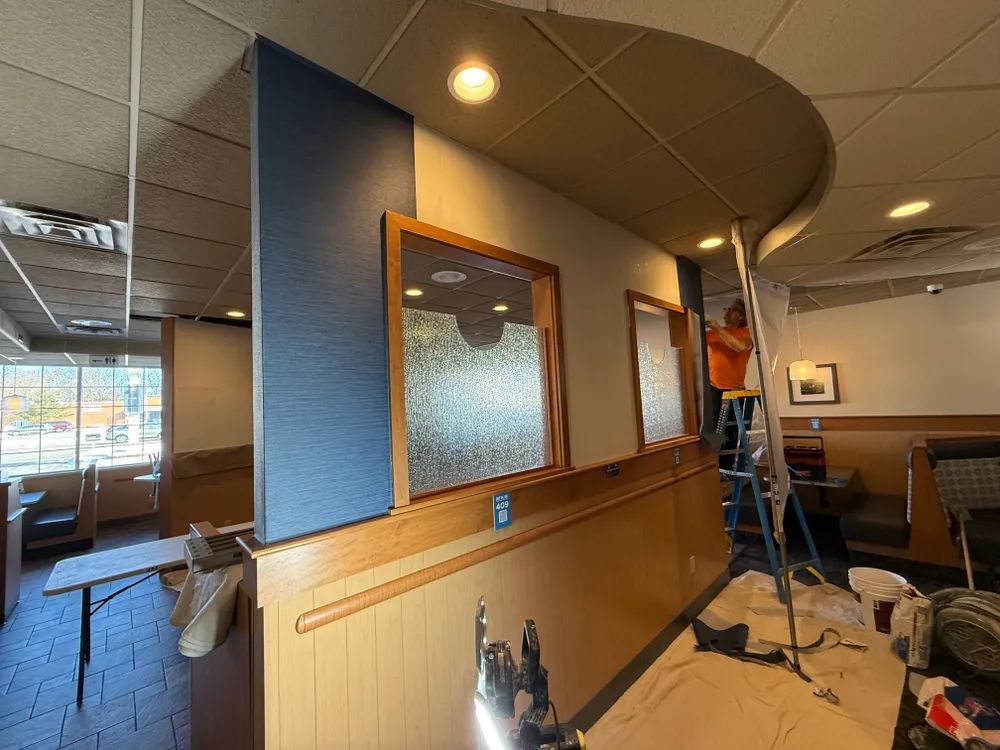 A man is standing on a ladder in a restaurant.