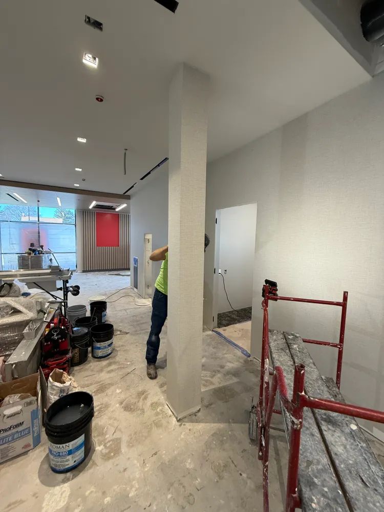 A man is standing in a room with buckets of paint on the floor.
