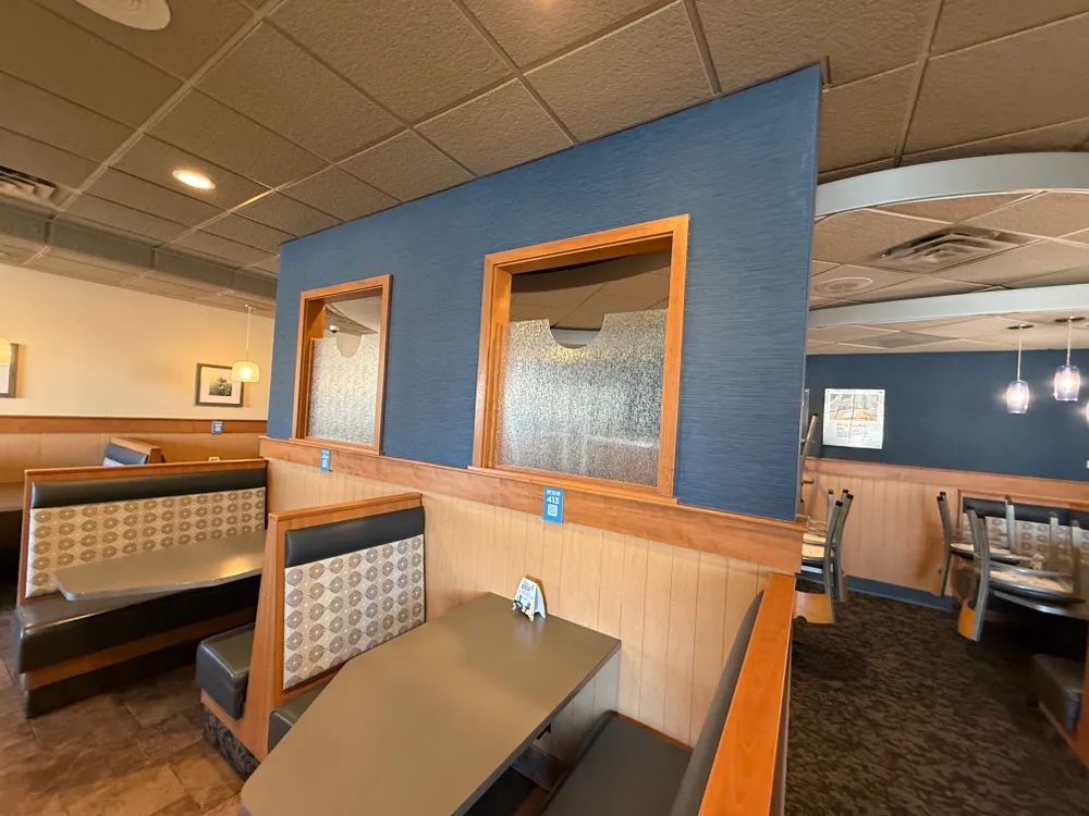 A restaurant with tables and benches and a blue wall