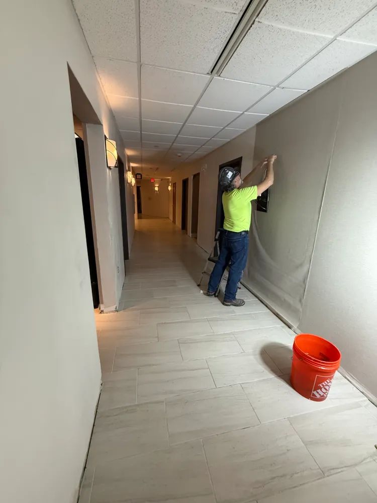 A man is painting a wall in a hallway.