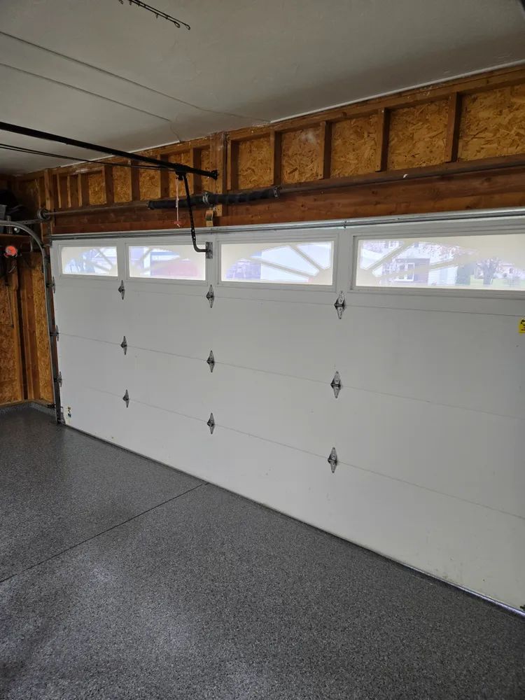 A garage with a white garage door and a gray floor.