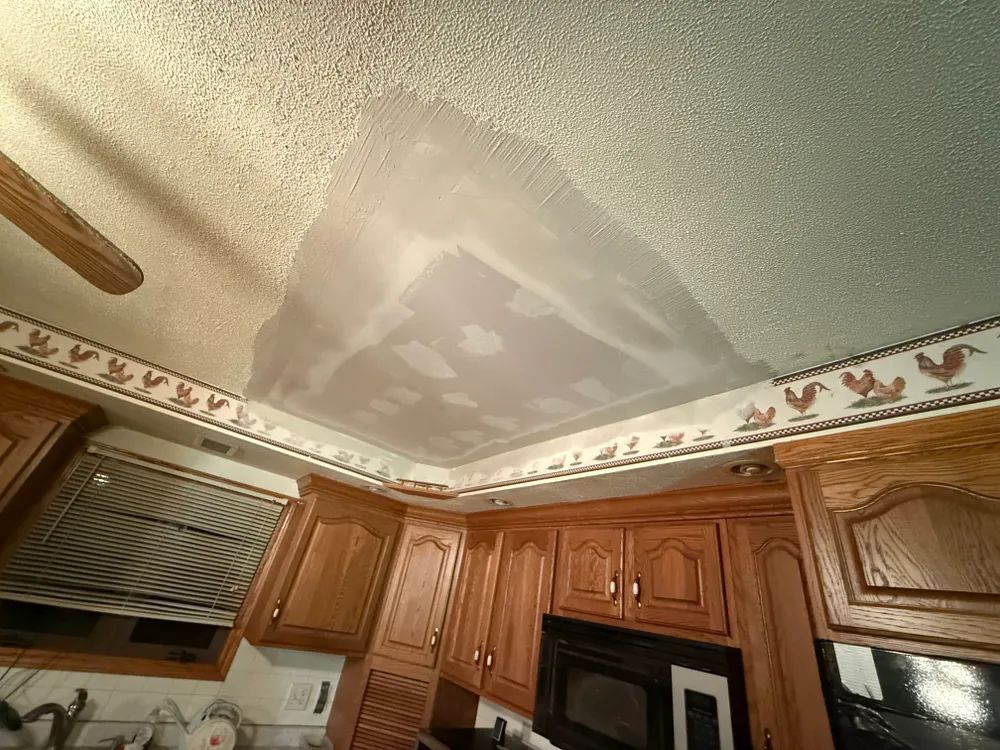 A kitchen with wooden cabinets , a microwave , and a ceiling fan.