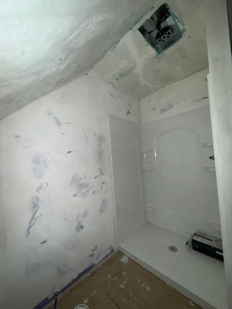 A bathroom with a shower stall and a fan on the ceiling.