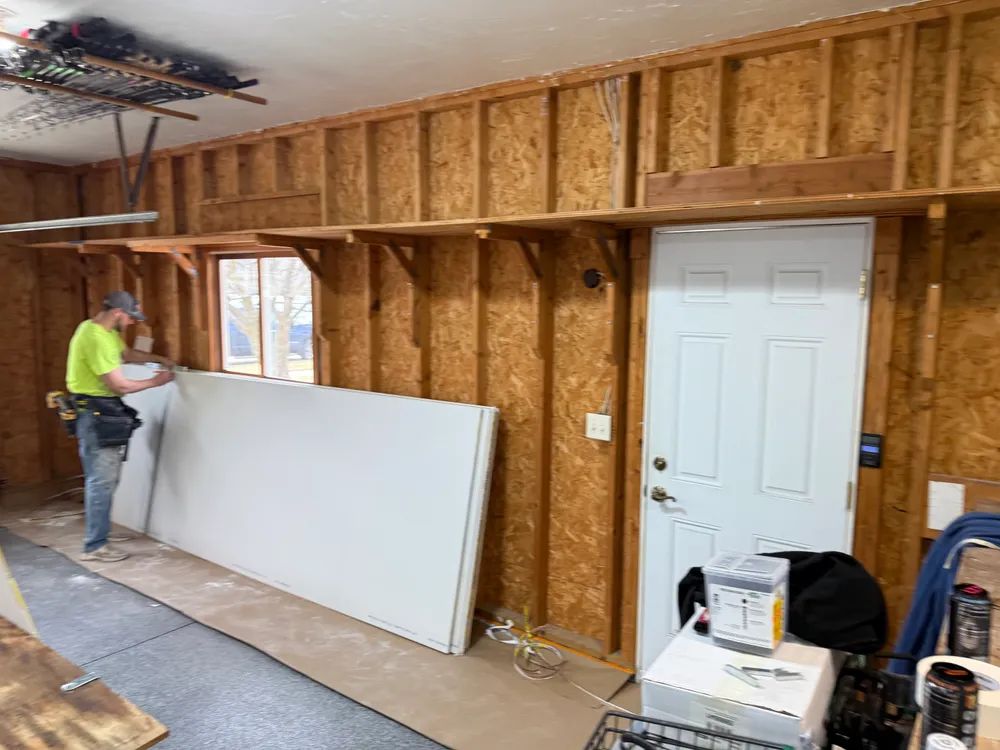 A man is working on a wall in a garage.