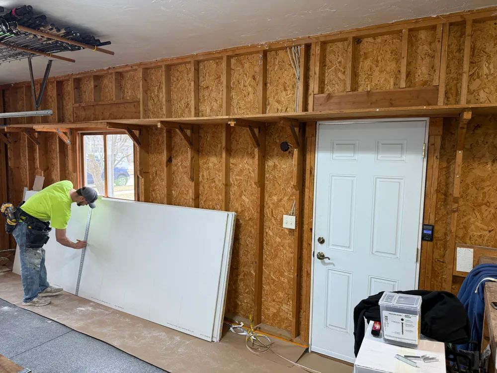 A man is working on a wall in a garage.
