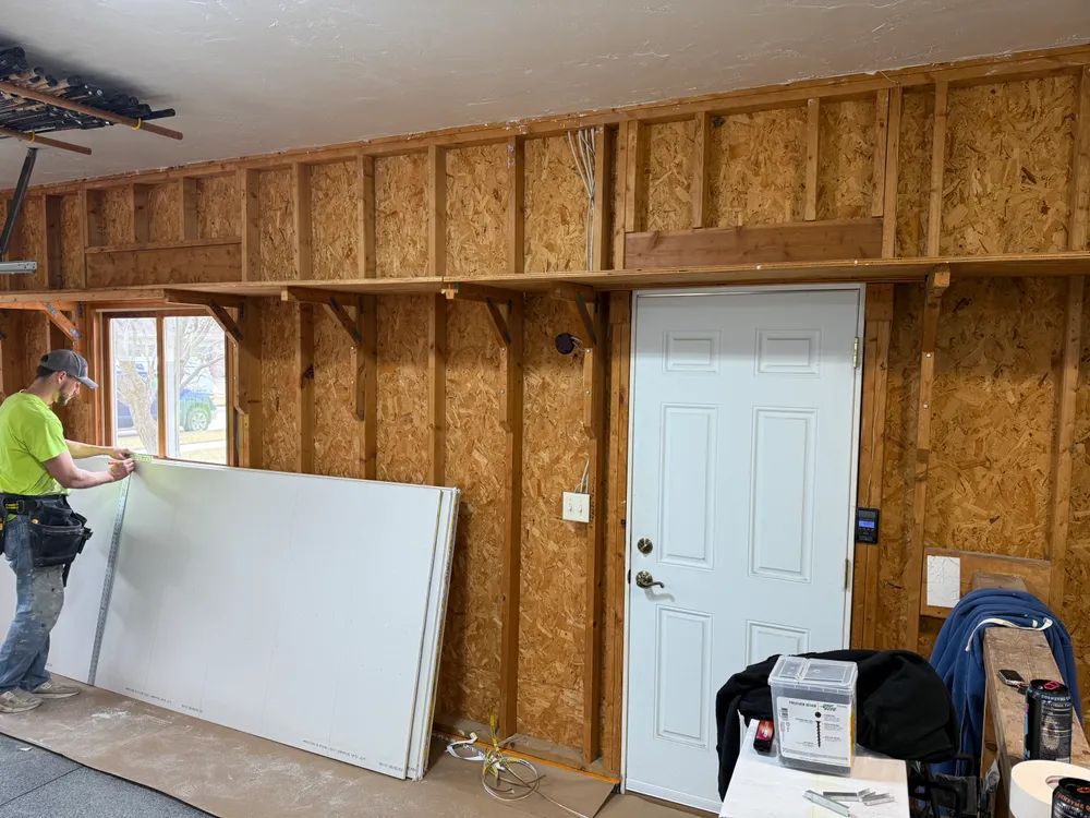 A man is working on a wall in a garage.