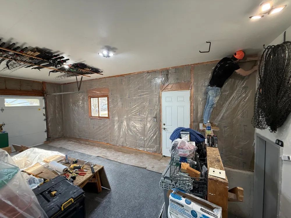 Two men are working on the ceiling of a garage.