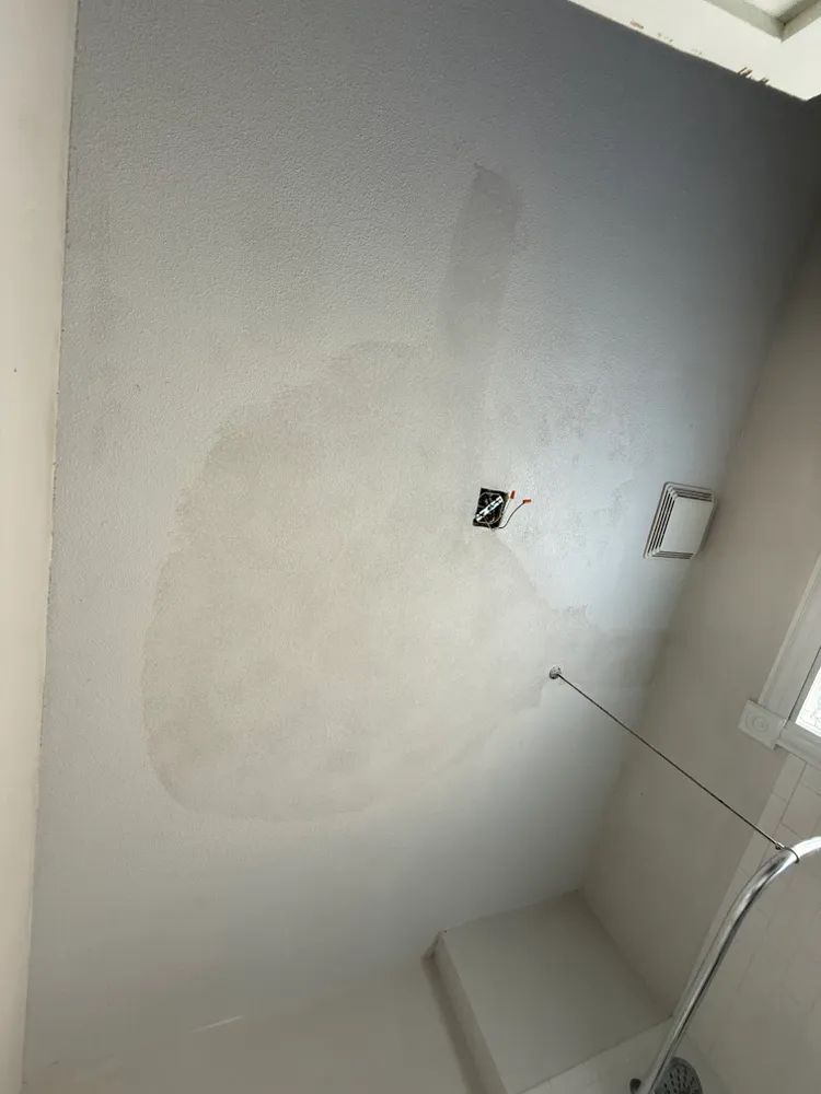 A bathroom with a ceiling that has a hole in it.